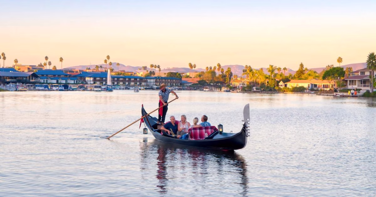 Gondola ride on Lake San Marcos with a couple enjoying a romantic sunset, surrounded by scenic waterfront views and palm trees.