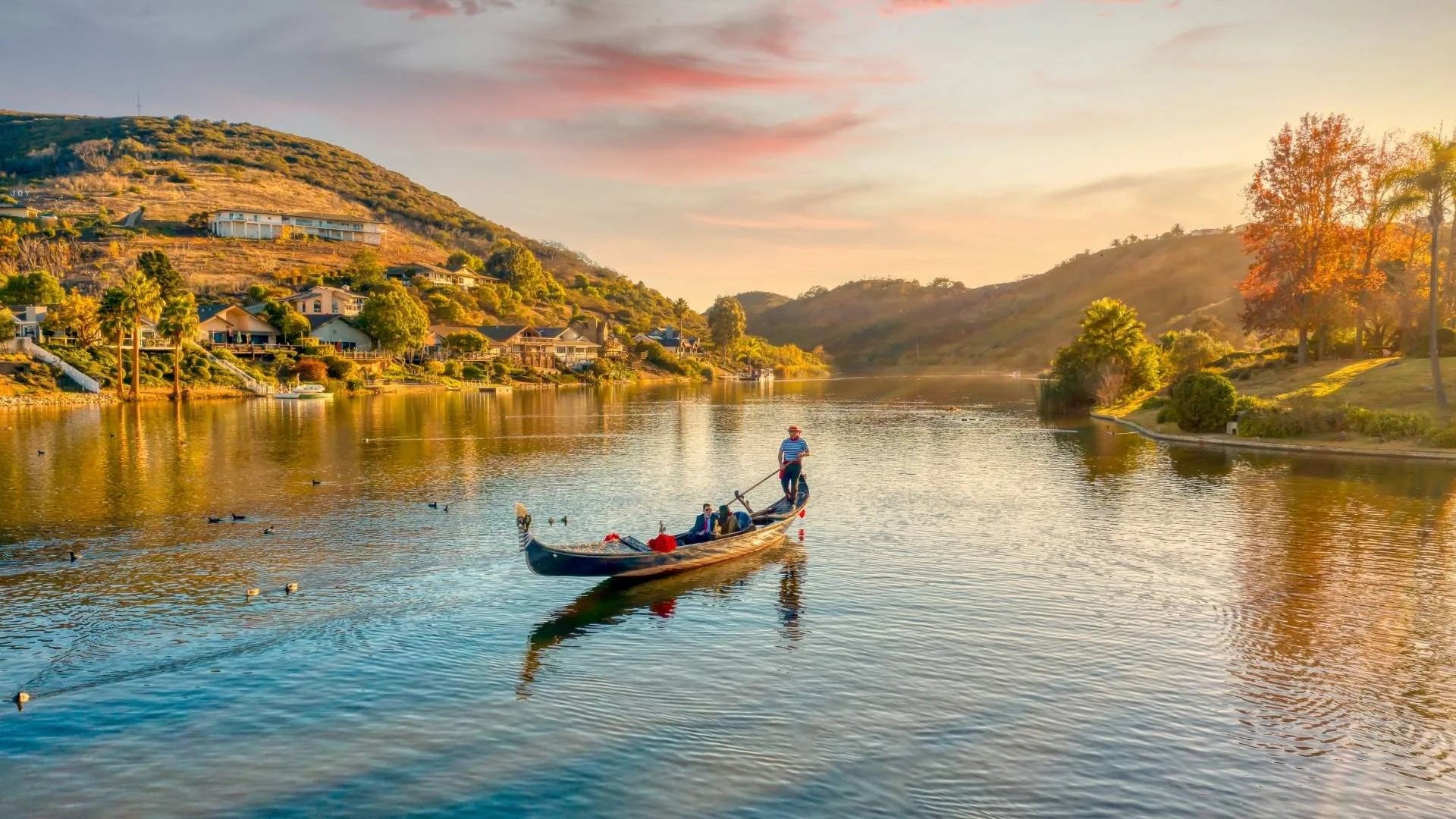 Gondola on calm waters at sunset, surrounded by scenic hills and waterfront homes, ideal for romantic marriage proposals in Carlsbad, CA.