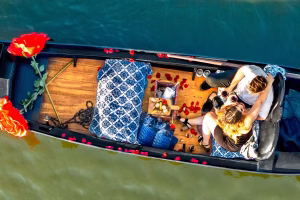 Couple enjoying a romantic gondola ride with rose petals and a cozy setup, highlighting Black Swan Gondola's intimate dining experience in San Diego.